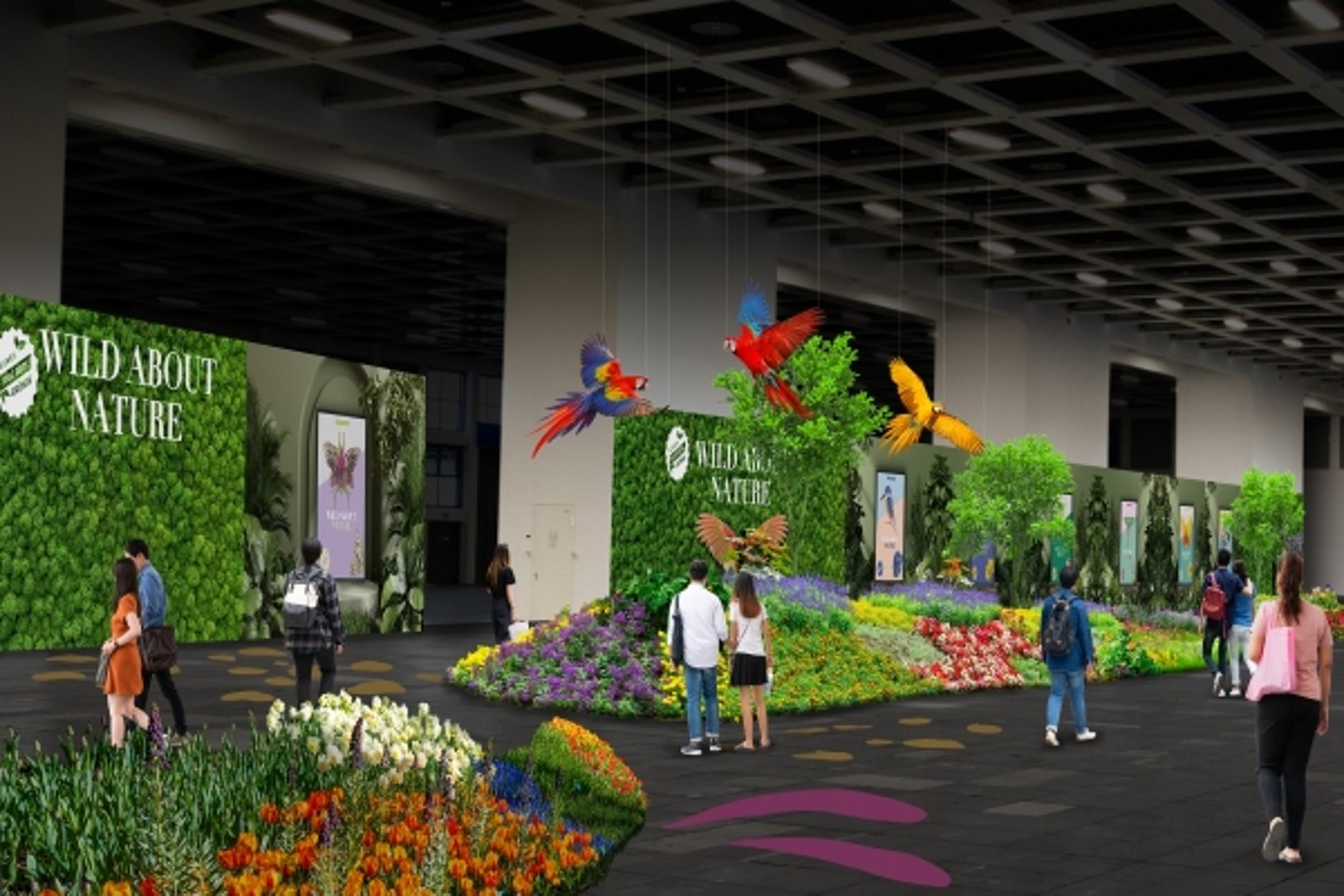 A graphic with large islands of flowers, printed partitions kept in green, parrot figures hanging from the ceiling, visitors walking between the islands of flowers. 