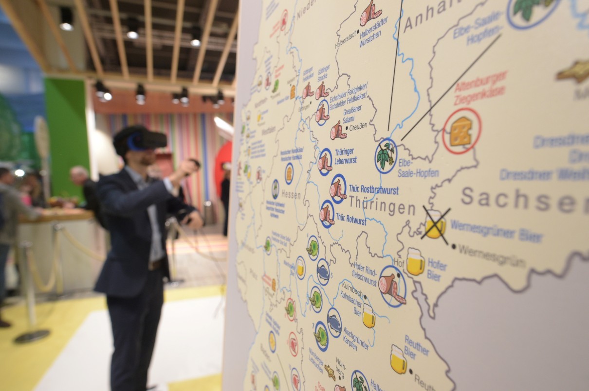 The map of Germany in a cutaway, being digitally explored by a man wearing virtual reality glasses. 