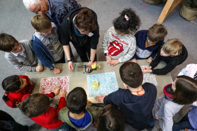 Kinder stehen um einen Tisch, beobachten ein Gerät zum Apfel schälen.
