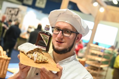 A man holding a Stollen and a bottle of gin.
