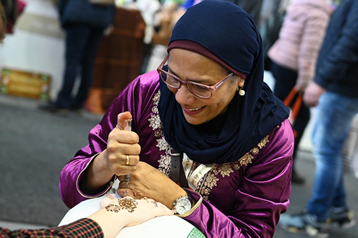 A woman painting a hand with 'henna' paint